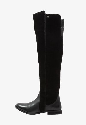 Altas botas negras con una combinación de ante y cuero, que presentan un diseño elegante, punta redonda y una suela plana con un sutil detalle de costura.