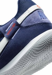 Jūras spēku zilo zamšādas sporta apavu modelis ar teksturētu adīto apkakli, baltām akcentiem un rakstainu gumijas zoli labākai saķerei. Sarkanā logotipa detaļa uz sāna.