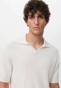 Svetr s krátkým rukávem, žebrovaný pletený v off-white barvě s výstřihem do V a texturovanou tkaninou, obsahující klasický límec a přiléhavý siluetu.