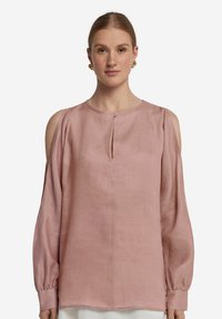 Ljusrosa linneskjorta med långa ärmar, kallaxelskärningar, knäppning och en smal nyckelhålöppning vid halsen.