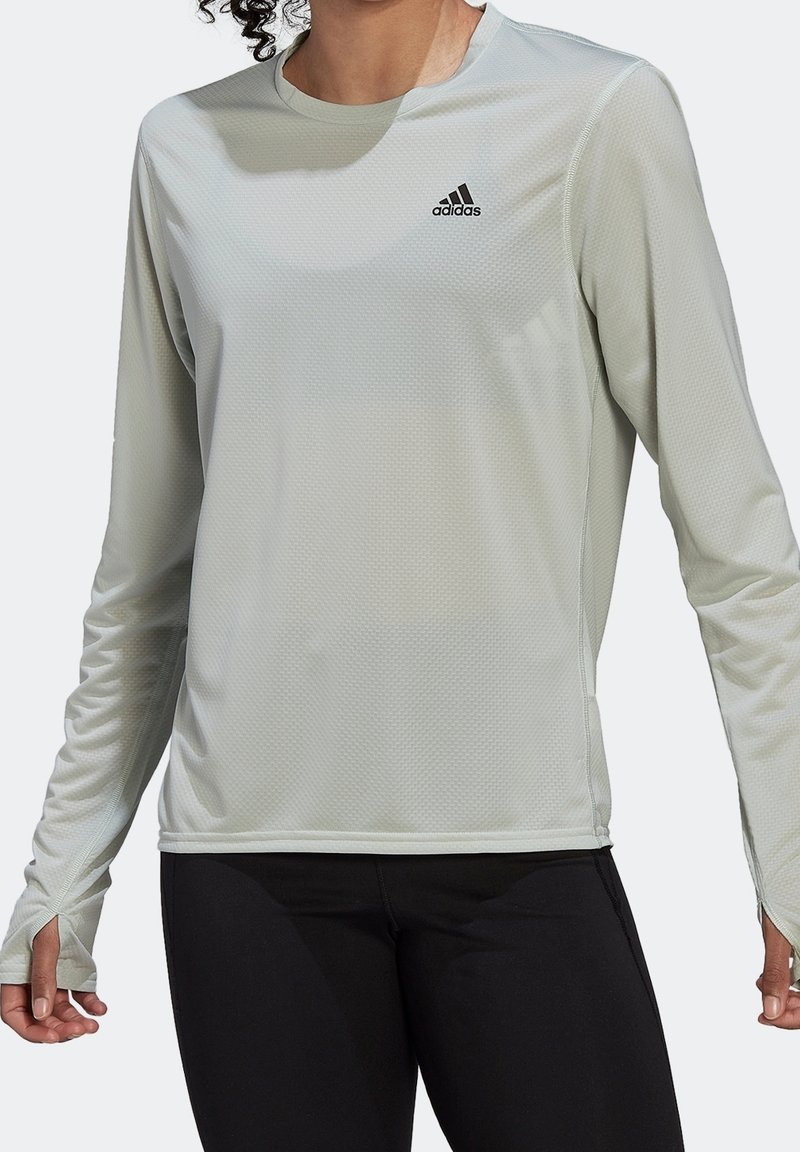 Ljust grå långärmad träningsskjorta med texturerad tygfinish, med rund halsringning och svart Adidas-logotyp på bröstet.