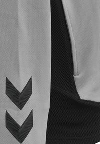 Pantaloni sportivi grigi e neri con un design testurizzato. Presentano due motivi a chevron neri sulla parte grigia e dettagli in tessuto liscio.