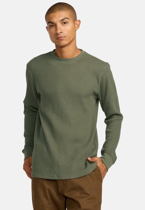 Langslippige, olijfgroene wafelstructuur shirt met een ronde hals en geribbelde textuur. Voorzien van een subtiele logolabel nabij de onderzoom.