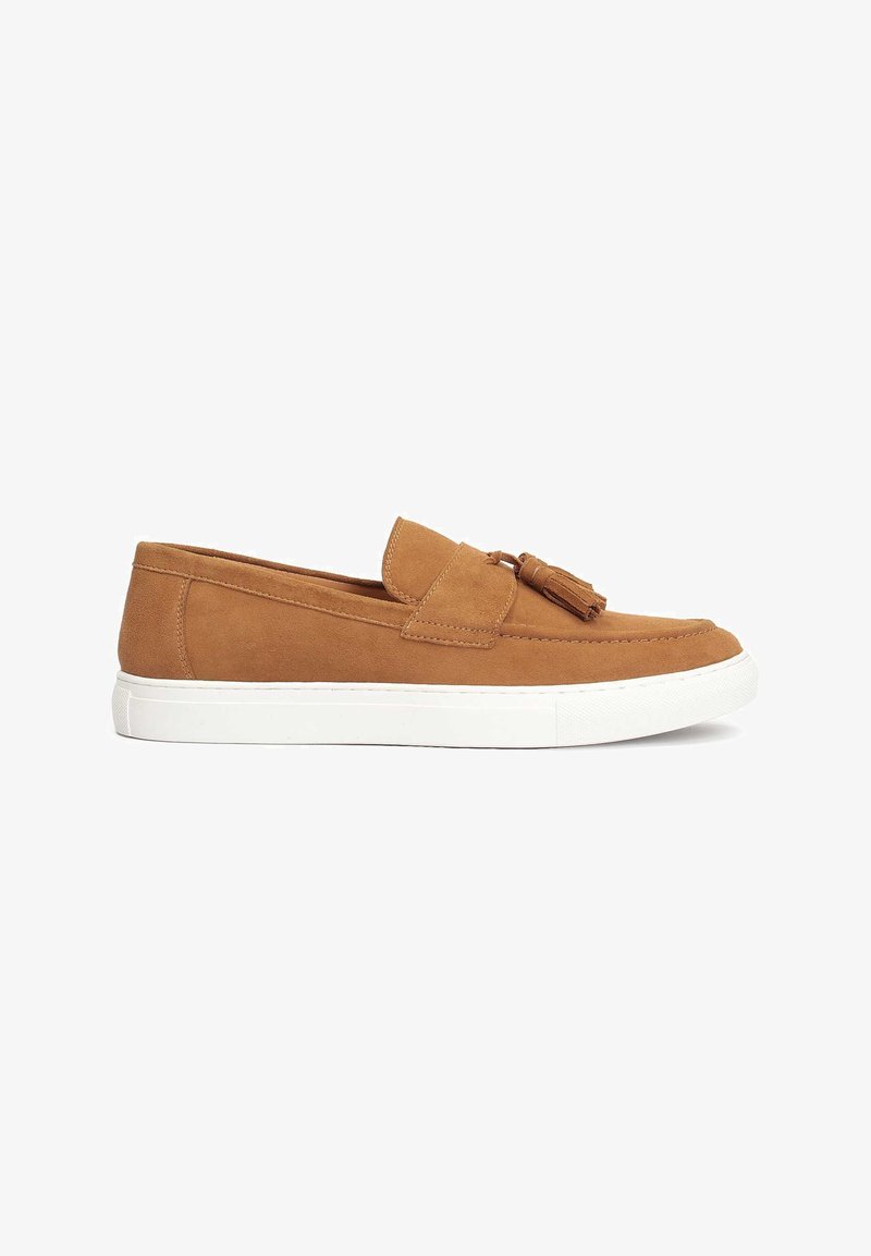 Baskets en daim marron clair sans lacets avec semelle en caoutchouc blanche et détail pompon sur le dessus, vues de côté sur fond blanc.