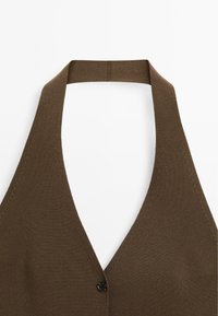 Top in maglia marrone con design a V profondo. Presenta una fascia posteriore e una chiusura con un singolo bottone nero davanti. Texture liscia.