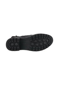 Semelle noire d'une chaussure avec une texture antidérapante, dotée de crampons multidirectionnels pour une meilleure traction et d'un design de talon lisse et arrondi.