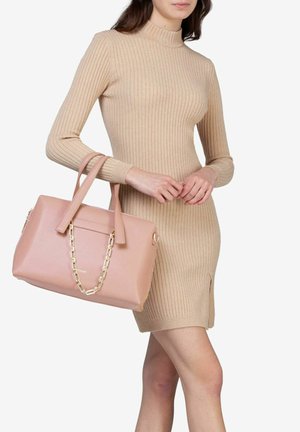Beige geribbelde gebreide jurk met lange mouwen, gecombineerd met een lichtroze handtas met kettingaccenten en dubbele handvatten.