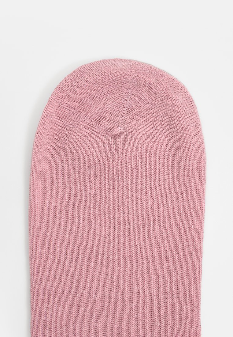Różowa dzianinowa czapka z zaokrąglonym czubkiem, ciasno utkana, o gładkiej fakturze. Brak widocznych wzorów lub elementów metalowych. Długość zakrywa czoło.