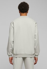 Ljusgrå sweatshirt med rund halsringning, ribbade cuffs och nederkant. Slät textur, lös passform och minimalistisk design.