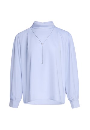 Hellblaue Bluse mit langen Ärmeln und hohem Kragen sowie plissierten Schultern, kombiniert mit einer dünnen silbernen Halskette mit zwei kleinen Anhängern.