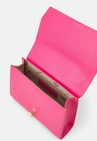 Sac en cuir rose texturé avec une fermeture magnétique, doté d'un intérieur beige et d'une poche zippée. Vue ouverte montrant le design intérieur.