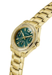 Orologio dorato con quadrante verde, forma ottagonale, tre sottodial e dettagli in cristallo attorno alla lunetta. Bracciale a maglie metalliche.