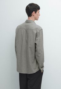 Camicia a maniche lunghe a quadri in marrone e crema, con colletto button-down e vestibilità comoda, vista da dietro con le maniche ripiegate.