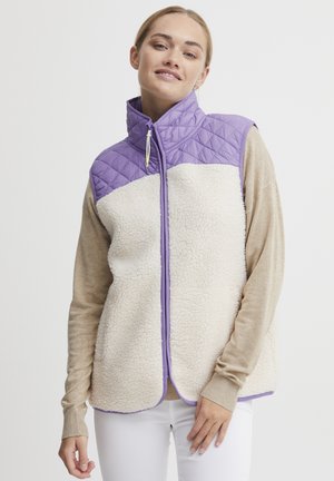 Gilet matelassé avec une partie supérieure lavande et une partie inférieure en polaire crème, présentant un col haut, une fermeture zippée et des détails en bordure violette.