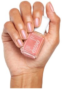 Vernis Essie dans un flacon en verre, couleur corail rose clair, tenu dans une main avec des ongles soigneusement manucurés, finition satinée, étiqueté "effets spéciaux".