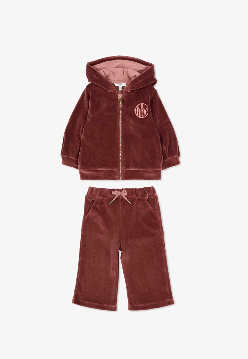 Bordowy welurowy dres dla dzieci, zawierający zapinaną na zamek kurtkę z kapturem i logo oraz pasujące spodnie z elastycznym pasem i sznurkiem.