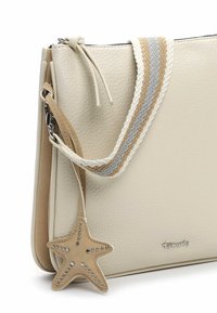 Kreemja tekstuuriga nahast käekott triibulise beeži-halli-valge kangast rihmaga ja tan-nahast meritähe kujulise ehe metallist tihvtidega.