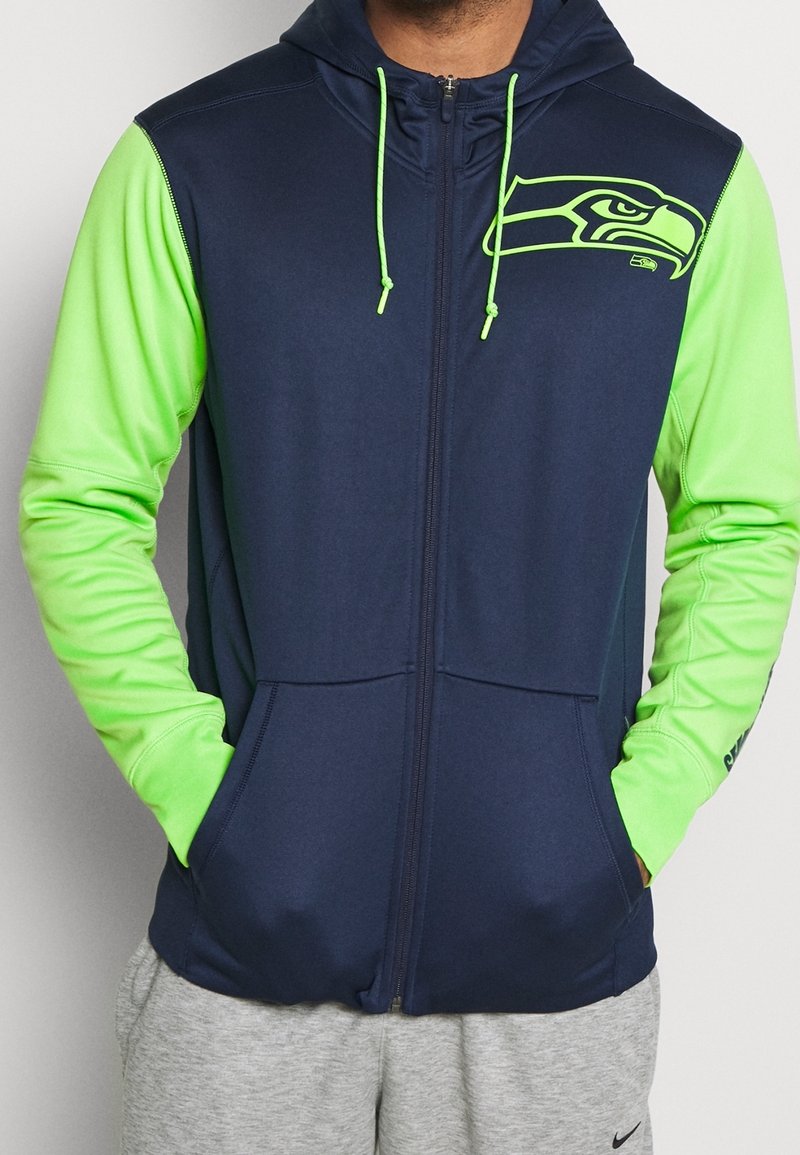 Navy blue zip-up hoodie with bright green sleeves and accents. Features a Seattle Seahawks logo on the chest and drawstring hood.