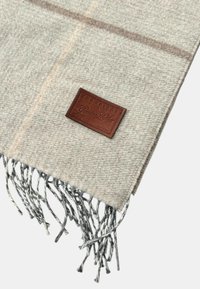 Sciarpa in misto lana beige con un motivo testurizzato, etichetta in pelle con testo stampato in rilievo e bordi frangiati in un colore contrastante.