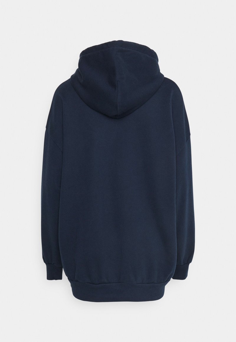 Haut à capuche bleu marine en pull, avec une texture douce, une coupe oversized, et des poignets et un ourlet côtelés. Dispose d'une capuche spacieuse à l'arrière.