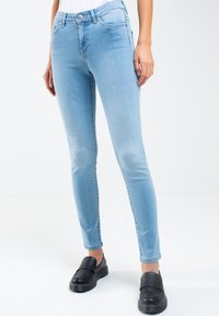 Ljusblå smala jeans i denim med en mjuk yta, som har framfickor och en midjehöjd som är medelhög, parat med svarta slip-on skor.