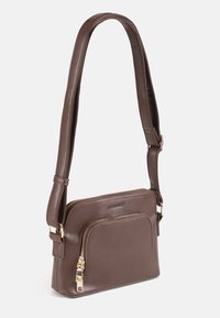 Bolso cruzado de cuero marrón con correa ajustable, compartimento principal y bolsillo delantero con cremallera y herrajes en tono dorado.
