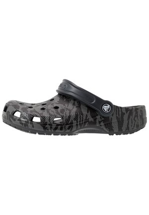 Sabot slip-on camouflage noir et gris avec des trous de ventilation et une bride de talon réglable, avec un logo circulaire sur la bride latérale.