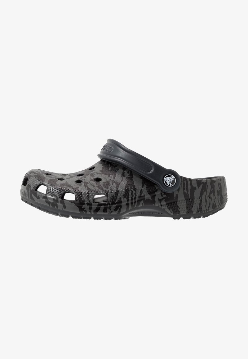 Sabot slip-on camouflage noir et gris avec des trous de ventilation et une bride de talon réglable, avec un logo circulaire sur la bride latérale.