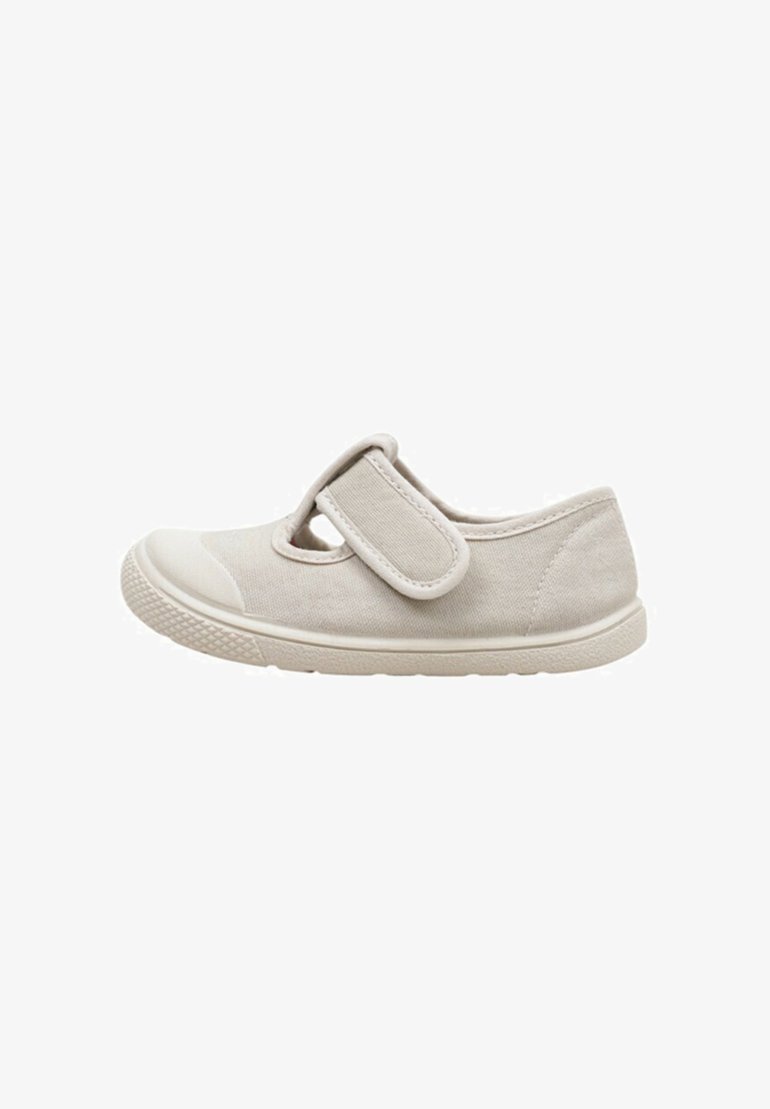Zapato de tela beige con punta redonda, correa de velcro y suela de goma texturizada. Parte superior lisa con detalles de costura y un diseño clásico.