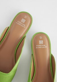 Zelené látkové nazouvací boty s hladkou hnědou stélkou, s nápisem "FOREVER COMFORT" a velikostními označeními uvnitř.