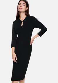 Schwarzes, knielanges Kleid mit 3/4-Ärmeln. Mit einem Schlüssellochausschnitt und taillierter Silhouette. Aus glattem, strukturiertem Stoff gefertigt.