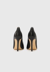 Sorte høye hæler med glatt lærfinish, spiss tå og tynn stiletthæl. Har merkevarens logo på hælen.