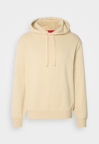 Sweat à capuche beige avec cordon de serrage, texture douce, poignets et ourlet côtelés, arborant un logo discret sur la poitrine. Design simple et décontracté.