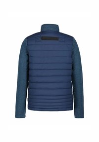 Marineblå polstret jakke med ribbede blå strikærmer, høj krave og bagløkke detalje. Vandret quiltet mønster på kroppen.