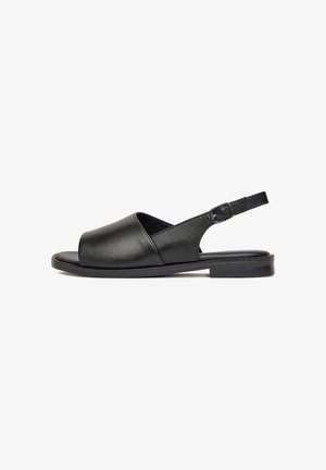 Czarne skórzane sandały z odkrytą palcą, wyciętym wzorem, regulowanym paskiem na kostkę i płaską gumową podeszwą. Minimalistyczny i elegancki design.