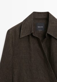 Mørkebrunt tekstureret uldfrakke med bred krave og synligt Massimo Dutti mærke inde i halsudskæringen.