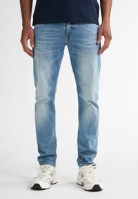 Jeans in denim azzurro chiaro con una vestibilità dritta, leggera scoloritura e design classico a cinque tasche. Abbinati a sneakers in tonalità neutra.