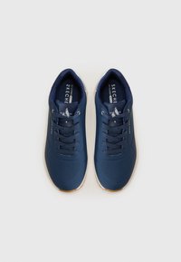 Baskets de sport bleu marine avec une tige synthétique lisse, un design perforé, une semelle en caoutchouc blanc contrastant et des lacets ronds.