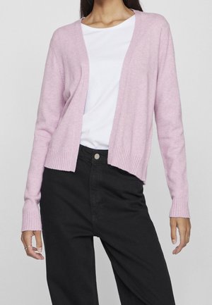 Light pink cardigan made of soft fabric, with a V-neck, open front, and ribbed cuffs and hem, worn over a white shirt and black pants.