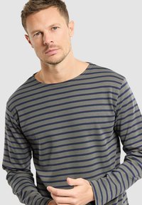 Camicia a maniche lunghe a righe con tessuto verde oliva e strisce orizzontali blu scuro, colletto rotondo e maniche sagomate.