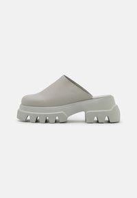 Lichtgrijze instapklompen met een gladleren bovenkant en een chunky, ribbelige rubberen zool met opvallende groeven voor grip.