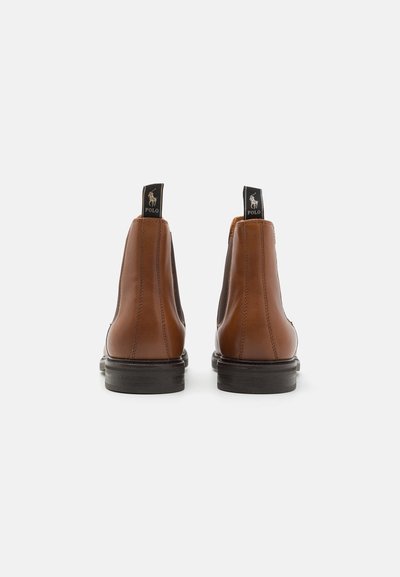Botas chelsea de couro castanho com painéis laterais elásticos pretos e costura de contraste. Apresenta uma etiqueta de puxar preta no calcanhar.