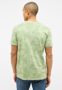 Grünes Kurzarm-T-Shirt mit einem strukturierten, Blattmuster, aus einem weichfallenden Stoff. Verfügt über einen Rundhalsausschnitt und einen geraden Saum.