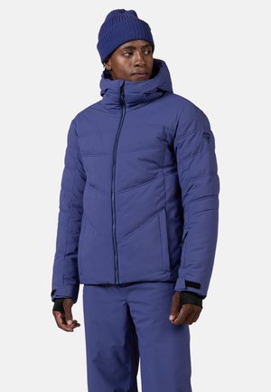 Lila Daunenjacke mit hohem Kragen und Reißverschluss. Mit einem Zickzackdesign, zwei vorderen Taschen und verstellbaren Bündchen.