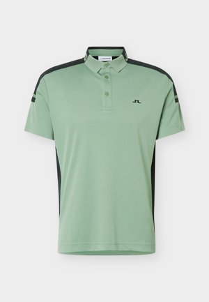 Lys grønn kortermet poloskjorte med svarte skulder- og sidepaneler, tre knapper i kragen og en liten svart logo på brystet.
