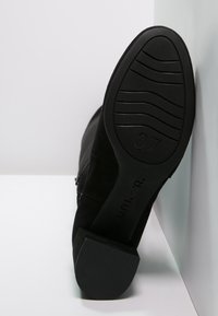 Black suede ankle boot with a square heel, textured rubber sole, side zipper, and size 37 marked on the bottom.