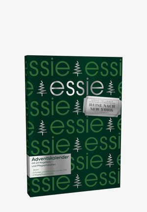 Boîte de calendrier de l'Avent verte avec le texte blanc "essie" et des icônes d'arbre, avec des accents argentés et une étiquette pour un concours de voyage à New York.