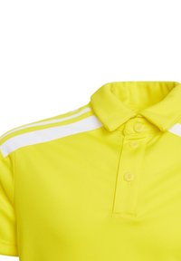 Polo shirt gialla con una texture morbida, caratterizzata da un collo a polo, tre bottoni e strisce bianche lungo le spalle.