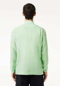 Camisa de manga larga a rayas verdes y blancas con puños abotonados, corte ajustado y cuello extendido, hecha de tela ligera.