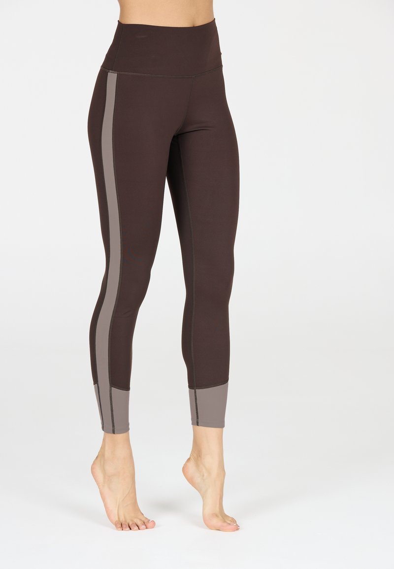 Leggings a vita alta di colore marrone scuro con pannelli laterali e polsini grigio chiaro. Tessuto liscio con cuciture piatte e design aderente.